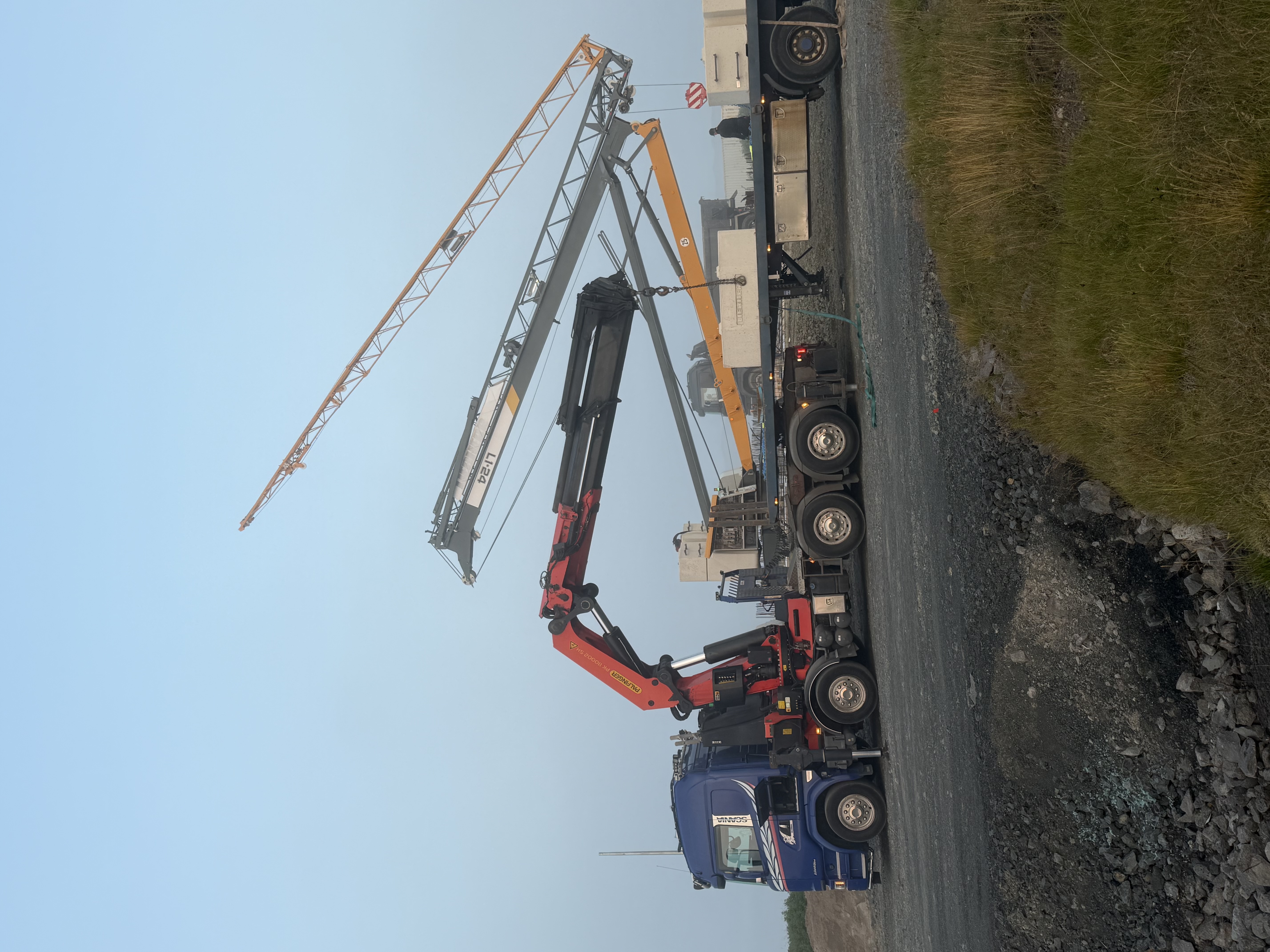Blár kranabíll og byggingakrani við framkvæmd.